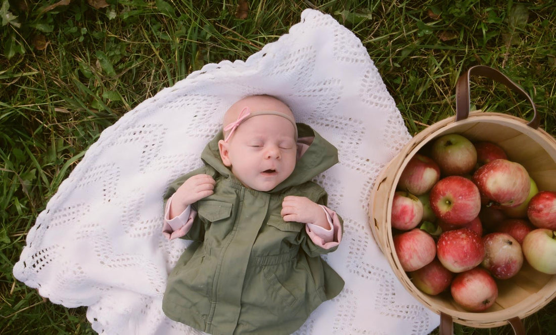 Top-down shot of sleeping baby on white knitted blanket over green grass, peaceful outdoor nap scene, gentle rest sleep aid for infants.