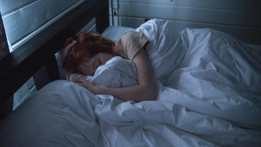 Red-haired woman sleeping peacefully in a dimly lit bedroom at night