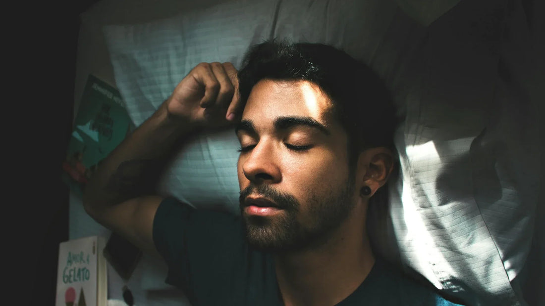 Young man sleeping peacefully on a bed with soft morning light.
