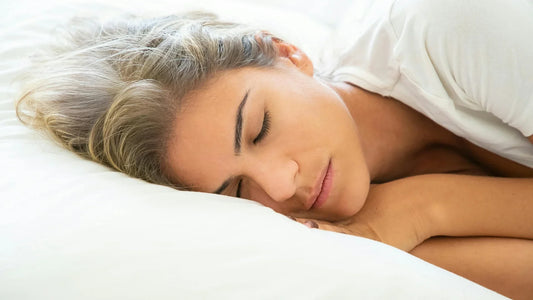 Blonde woman sleeping comfortably on soft white bed linen.