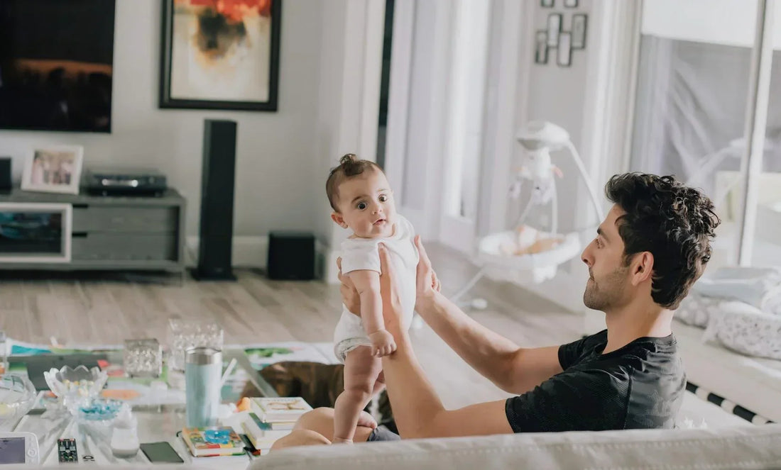 Father holding infant baby in bright family living room, cozy calm rest scene for baby soothing & parent relaxing sleep aid.